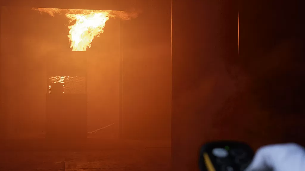 Harjoitustalon keittiö on tulessa. Kouluttajan kaukosäädin säätelee muun muassa palon voimakkuutta.